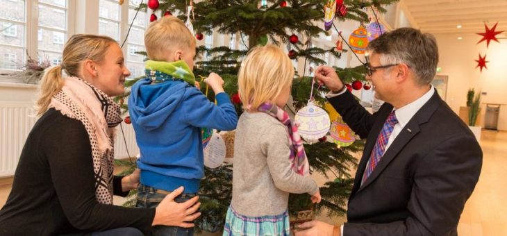 Kinder schmücken Weihnachtsbaum mit ihren Wünschen