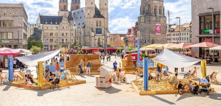 Kinder bauen Sandburgen an der Sandskulptur „Halle am Meer“